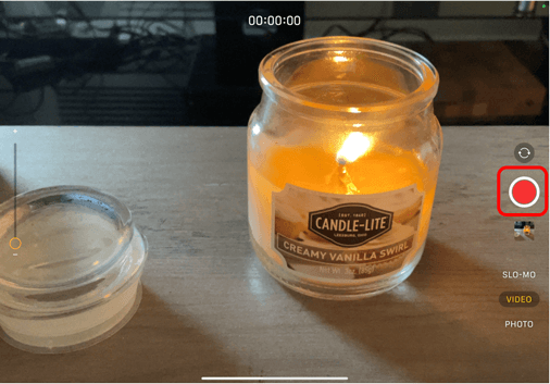 Camera on iPad pointing at a candle with Red recording button circled in red to show how to start recording a video