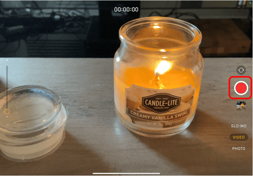 Camera on iPad pointing at a candle with Red recording button circled in red to show how to start recording a video

