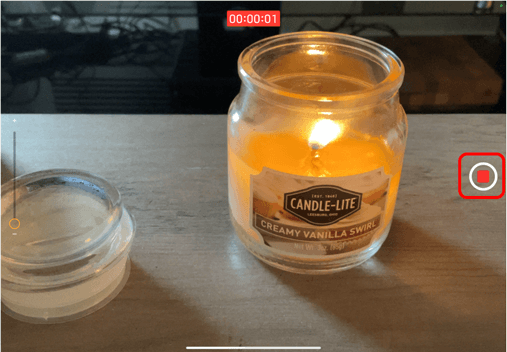 Camera on iPad pointing at a candle with the stop button circled in red to show how to stop recording a video
