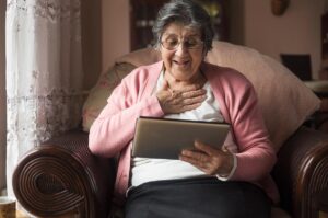 Older woman looking at tablet with smile on her face.