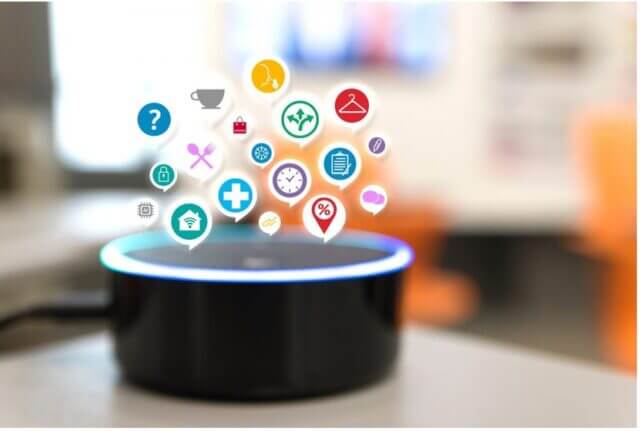 Black round smart speaker sitting on table with different app icons hovering over it for special effect.