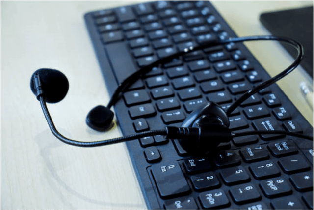 Black keyboard with black headset on top.